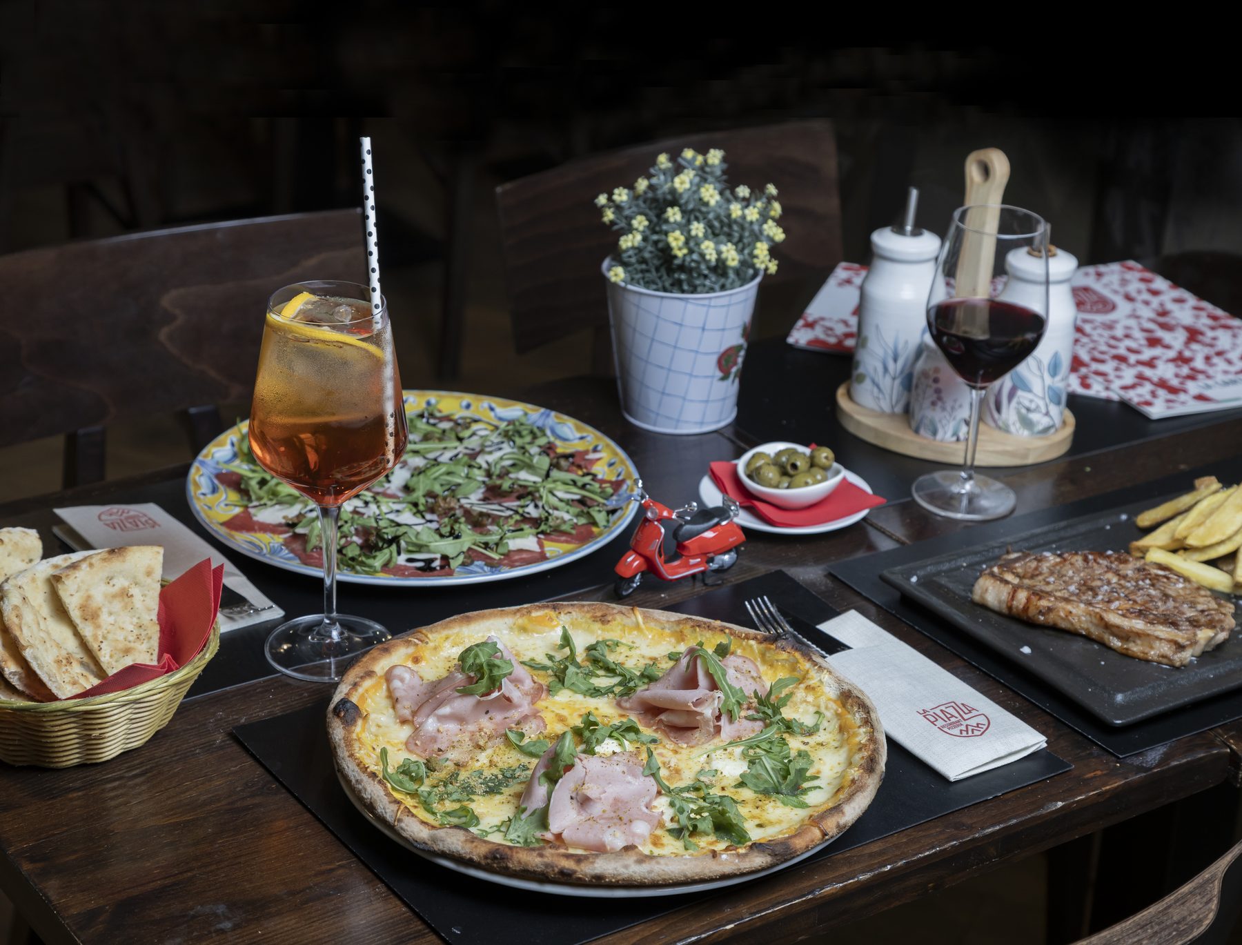 Mesa de La Piazza con pizza, carpaccio y la carta